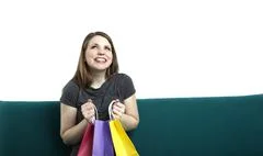 Portrait Of Young Happy Smiling Woman Sitting On A Sofa With Shopping Bags
